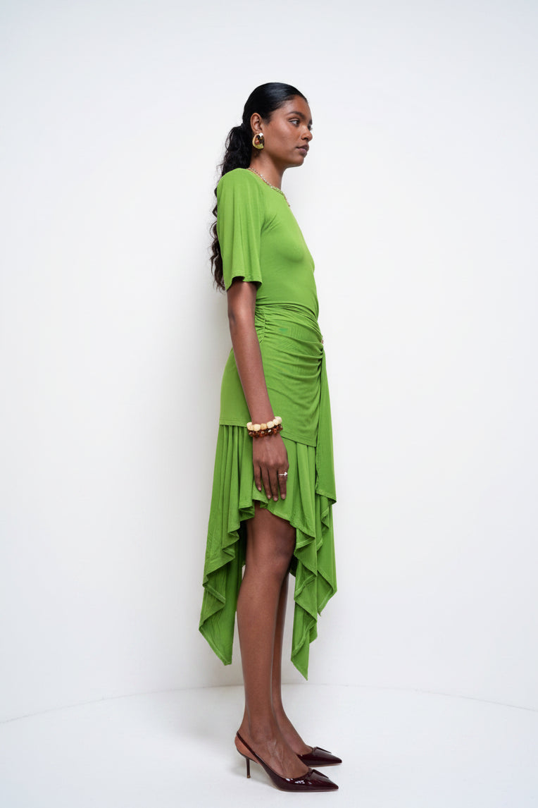 Woman wearing a green dress standing against a white wall